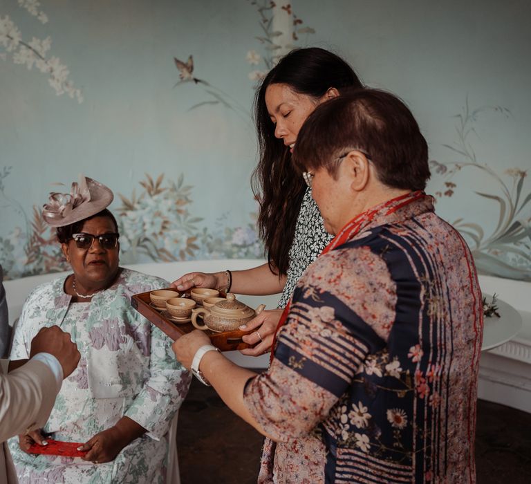 Groom in linen suit stands with wedding guests during traditional Chinese tea ceremony at Wasing Park wedding