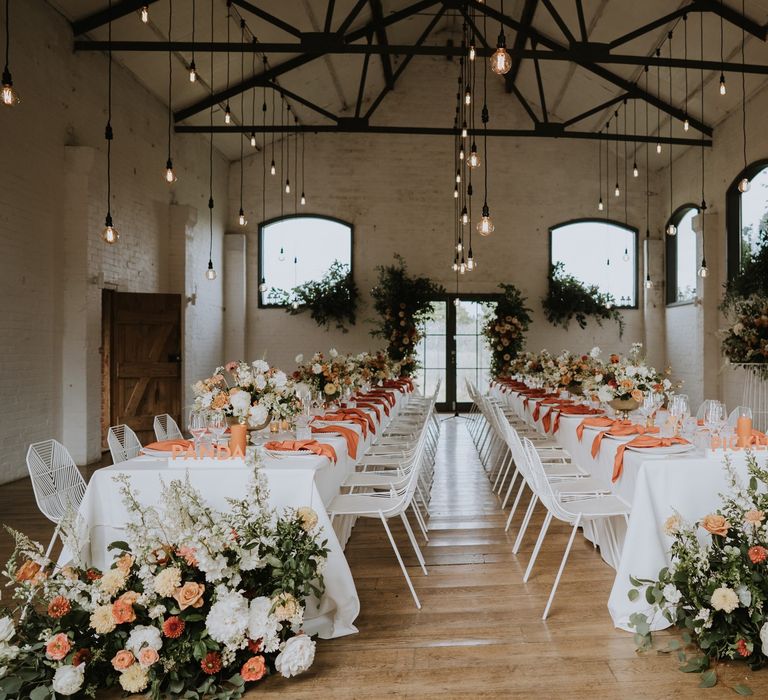 Stylish peach and white wedding reception decor and flowers with hanging festoon lights 