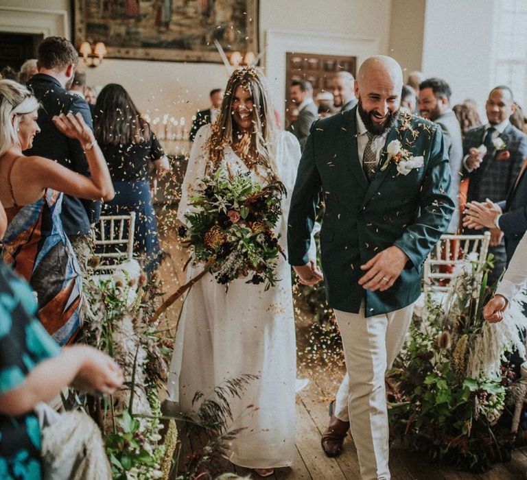 Bride & groom walk through confetti on wedding day at Elmore Court