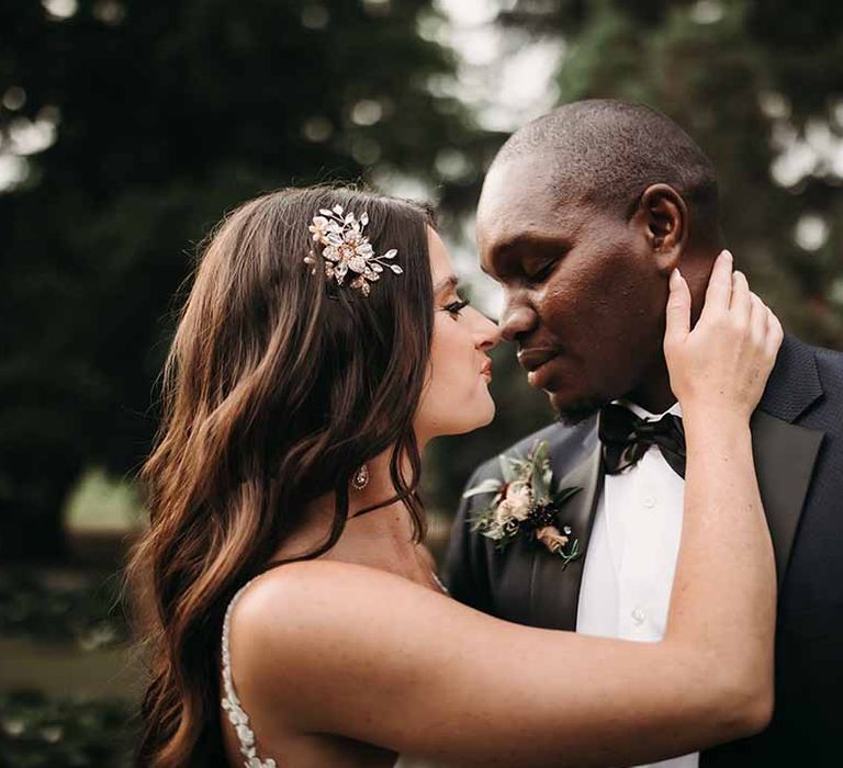 Bride wears simple sequin hair clip & kisses Groom in his black bow tie 