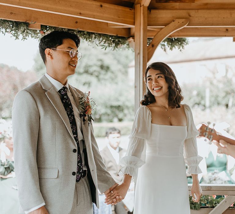 Bride & groom look lovingly at one another during wedding ceremony outdoors