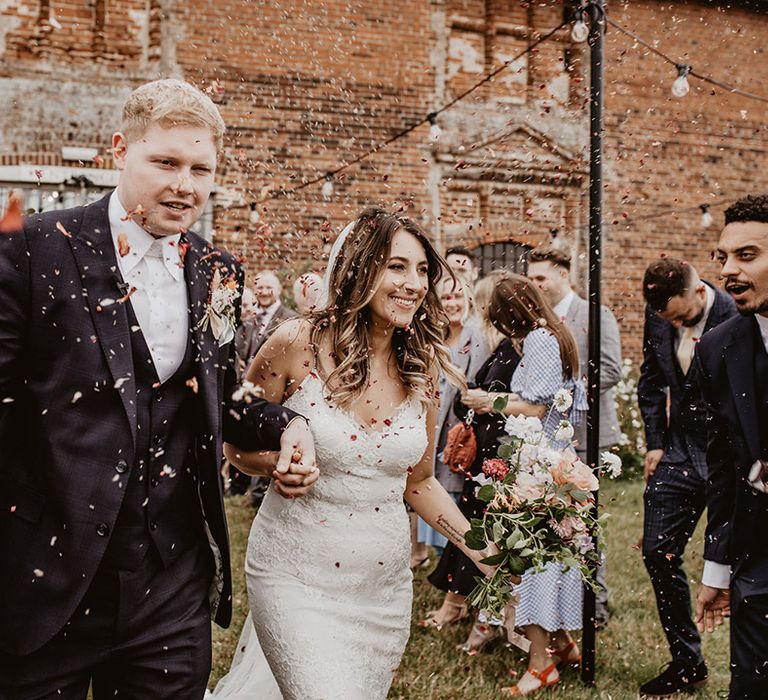 Bride & groom walk through confetti on their wedding day at Godwick Barn