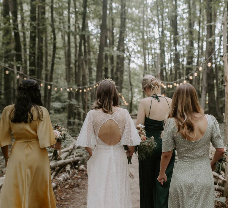 Bride walks with her wedding party as she wears wedding gown with V-shaped back 