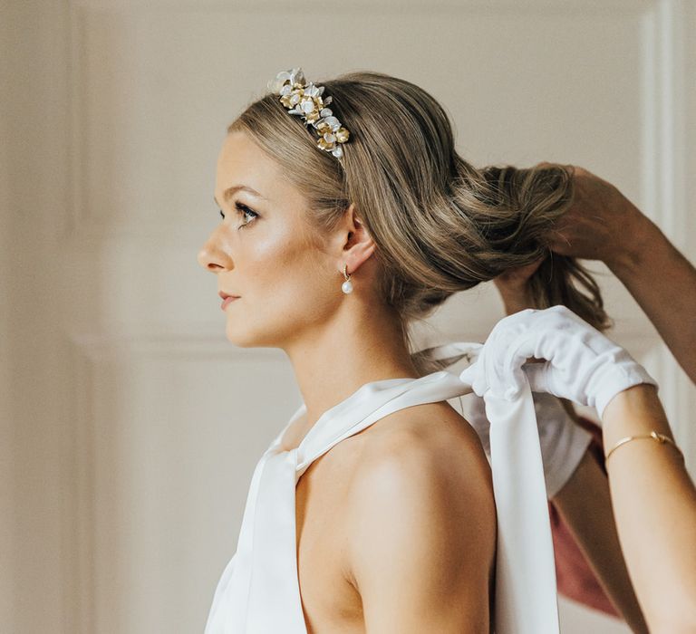 Bride with curled hair and bespoke floral headband has Halfpenny London wedding dress tied around her neck