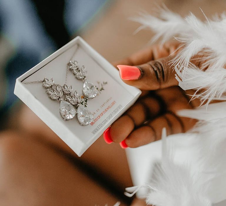 Bride holds box complete with her earrings and necklace for wedding day