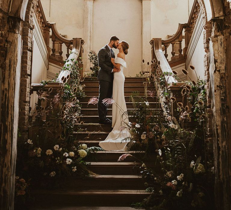 Bride & groom kiss on staircase on their wedding day 