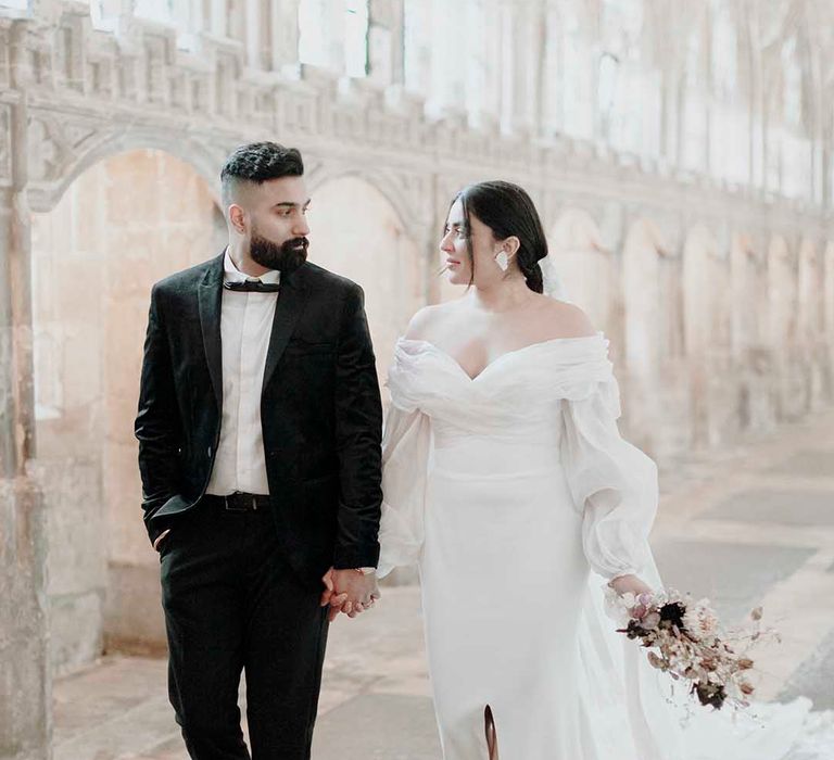 Elegant wedding at Blackfriars Priory with groom in a tuxedo and bride in an off the shoulder wedding dress with long sleeves 