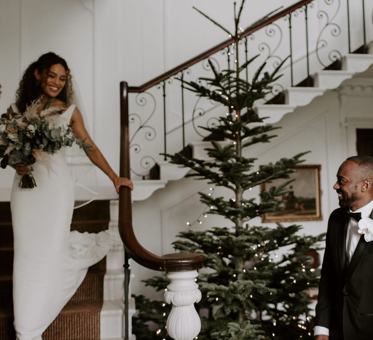 Bride walks down staircase as her mother and father watch on