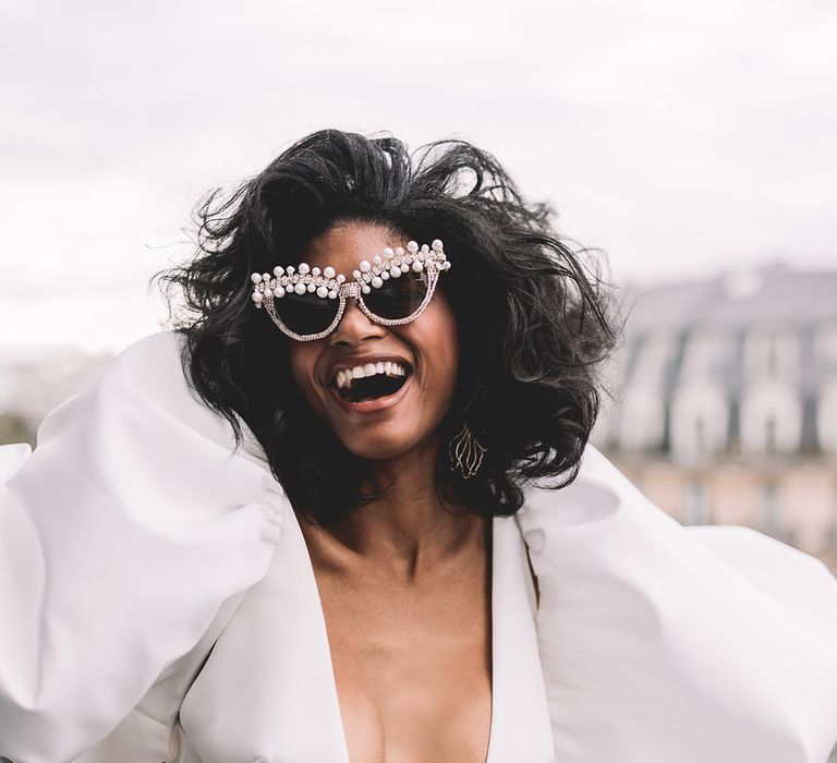 Bride in a puff sleeve wedding dress with plunging neckline and embellished sunglasses