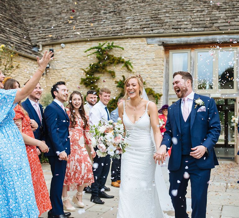 Confetti moment at Caswell House wedding venue with bride in an embellished wedding dress and groom in a navy suit with pink tie 