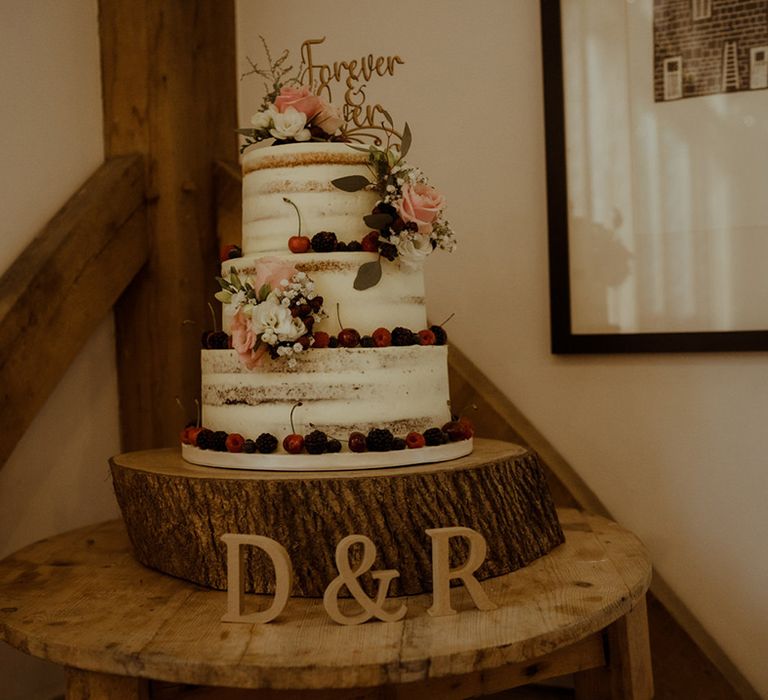 Rustic three tier wedding cake complete with naked icing and floral decor with fruit