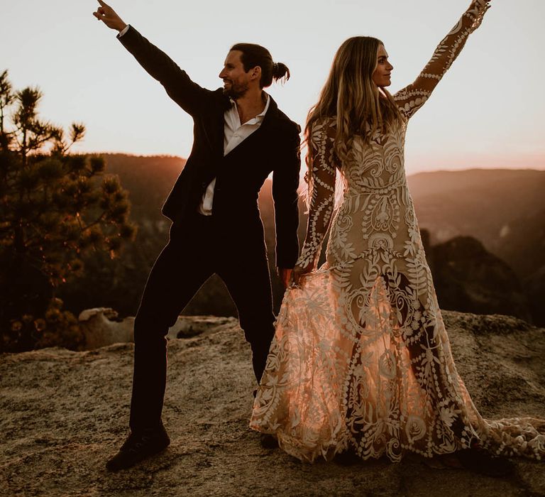 Bride & groom lift their hands and arms in the air