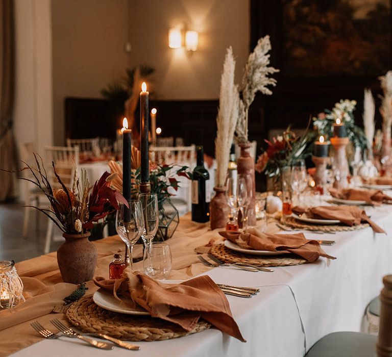 Boho chic tablescape complete with orange table runner and candles 