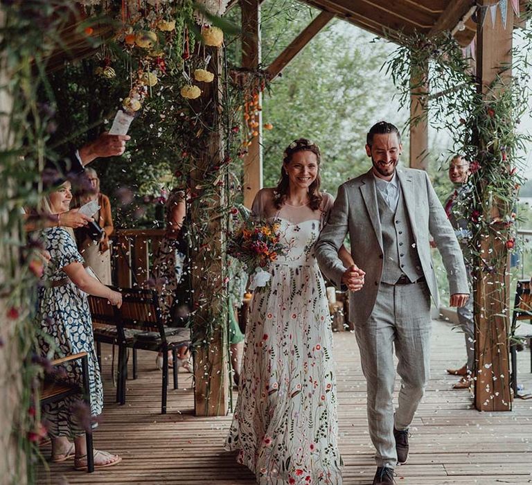 Bride and groom exit their wedding ceremony to confetti being thrown by wedding guests for botanical wedding 