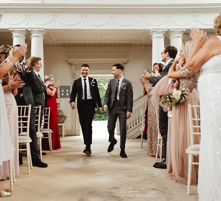 Wedding guests in sparkly outfits clap for grooms at the Compton Verney Gallery and Park 