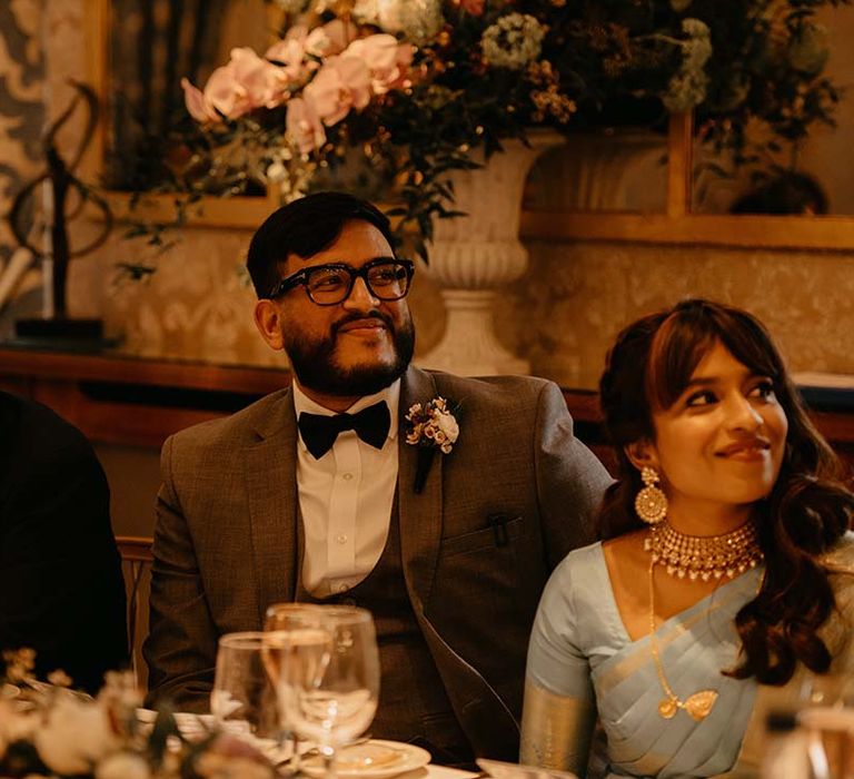 Bride in mint green saree with groom in grey suit with black bow tie and neutral boutonniere 