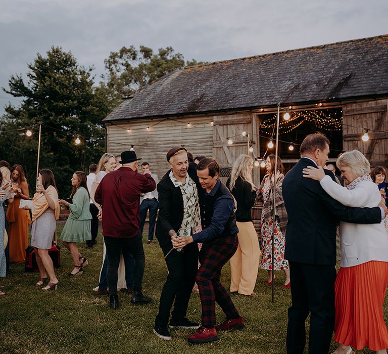 Wedding guests enjoy a fun dance outside The Secret Barn wedding venue in Sussex