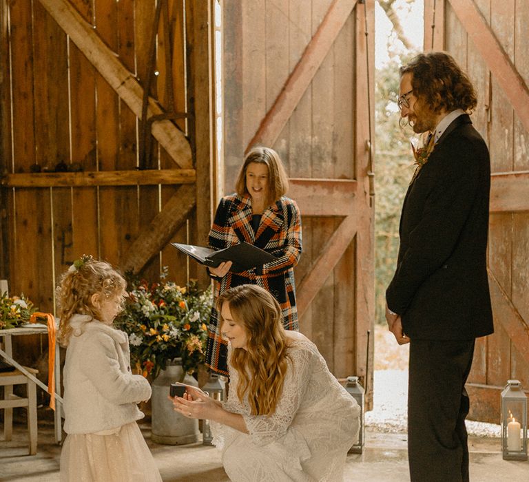 Flower girl in sparkly silver shoes and white fur jacket brings the ring box to the bride at Nancarrow Farm wedding