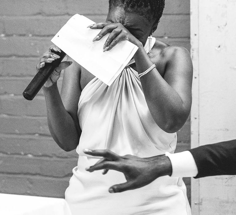 Family member in pink halter neck dress reads out speech and covers her face as she cries