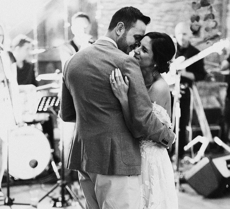 Bride and groom stand closely together as they have their first dance