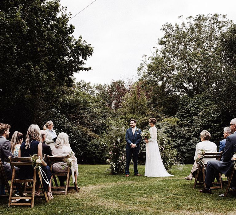 Bride and groom stand at the altar for outdoor wedding ceremony at Treseren with two flower columns for altar decor