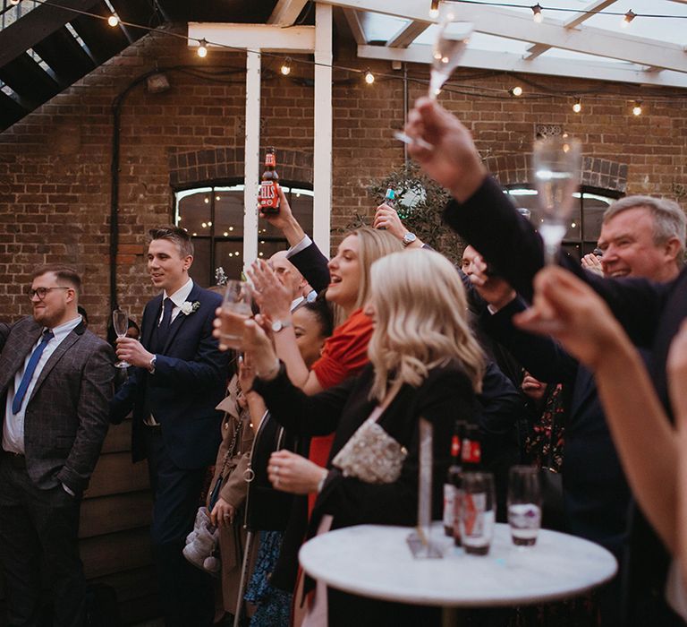 Wedding guests raise their drinks in a toast for the newlyweds during speeches 