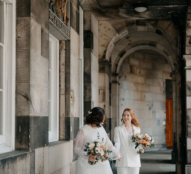 Bride leads her bride whilst holding her hand on their wedding day