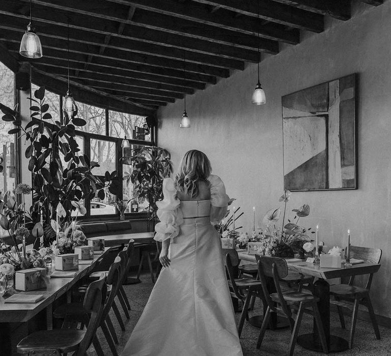 Bride with long wavy hair in JESUS PEIRO bridal separates standing in the middle of her wedding reception 