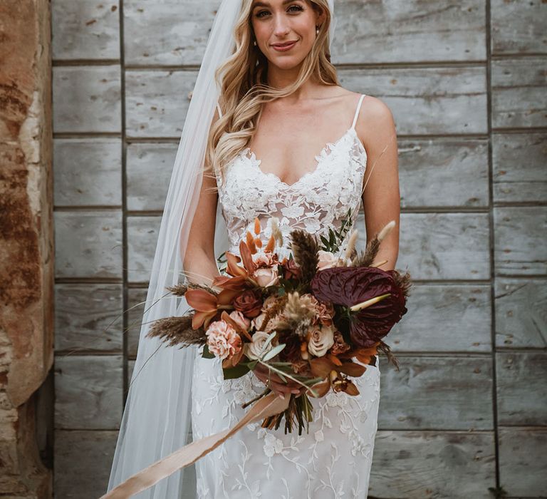 Bride wears Made With Love Bridal cathedral veil, Emmy Mae Bridal lace wedding dress and holds colourful floral bouquet 