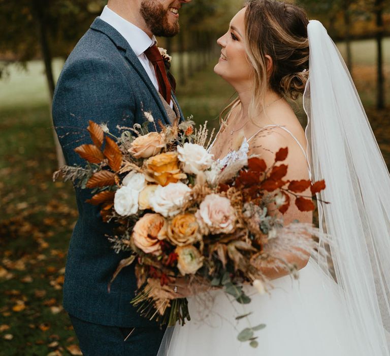 Bride and groom gaze and smile at each other as they pose for couple portraits 