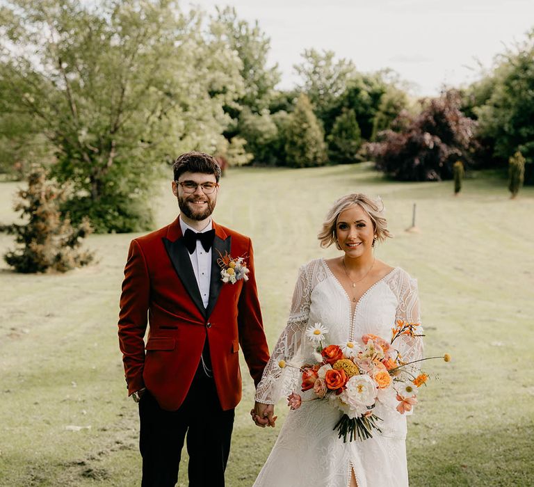 Bride in a boho wedding dress from Bibiluxe Studio with groom in an orange tux for retro wedding 