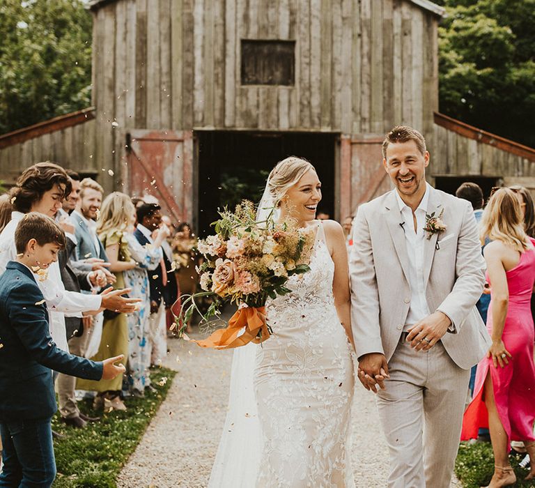 Bride and groom laugh together as they have their confetti moment exiting Nancarrow Farm wedding venue 