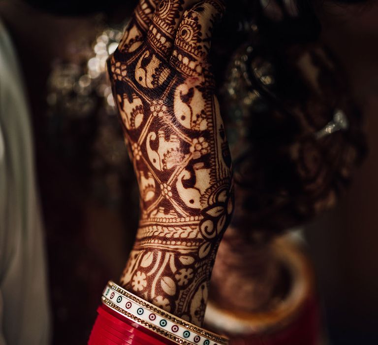 Bride wears traditional Mehndi with elephant pattern and red and gold bangles with colourful embellishment 