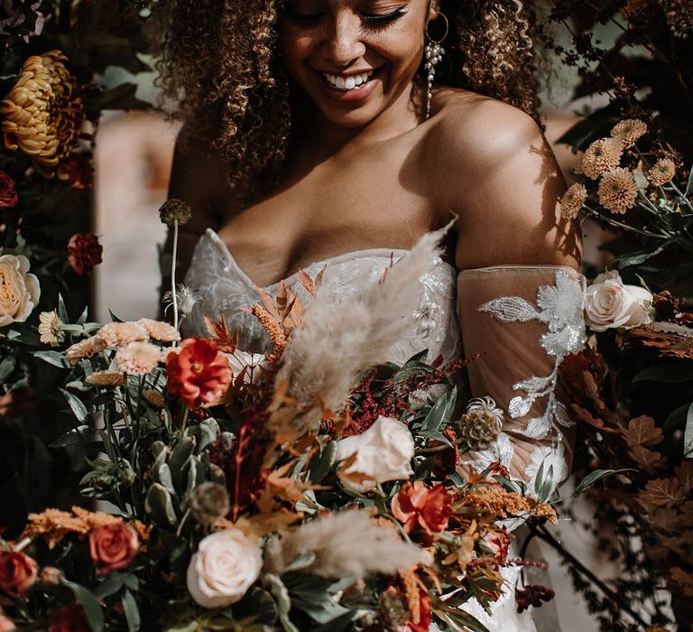 Bride in a corset style off the shoulder wedding dress with sparkles and sequins for an autumnal wedding with a glasshouse reception 