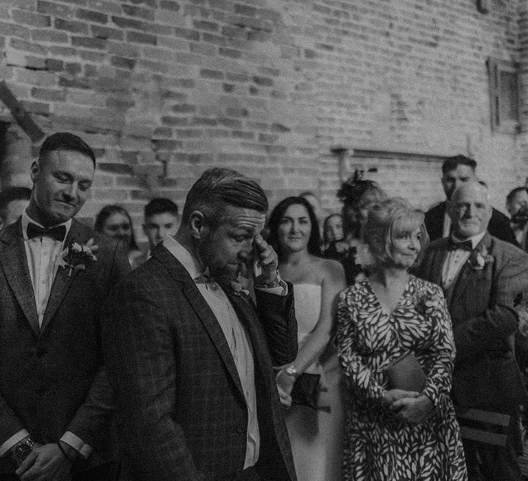 Groom wipes his eyes as the bride enters the aisle 