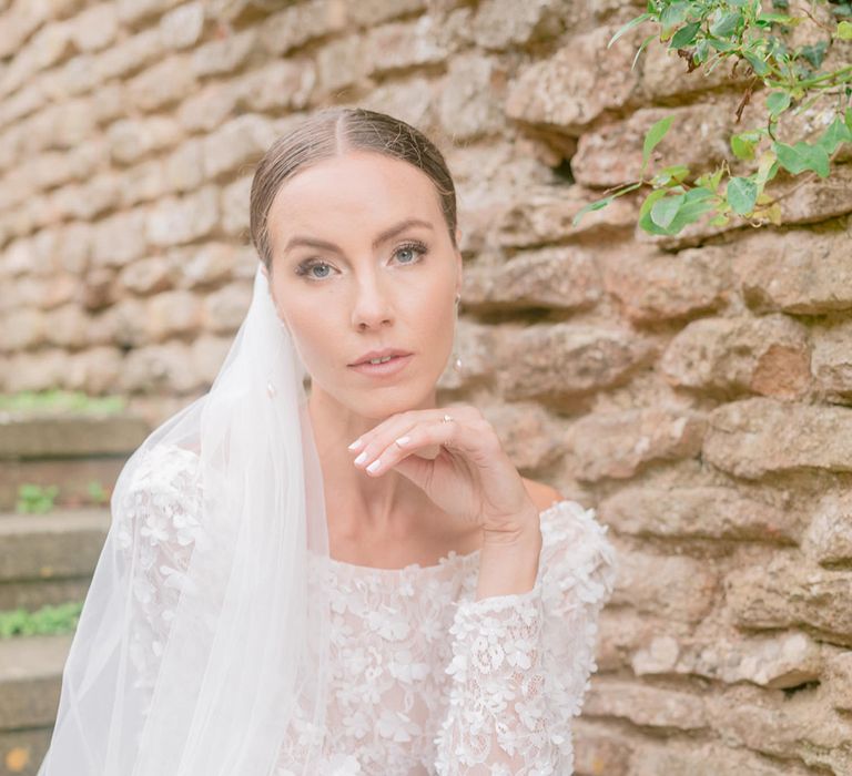 Bride with smoky eye makeup, white nails and a bespoke veil wearing a bespoke flower appliqué wedding dress