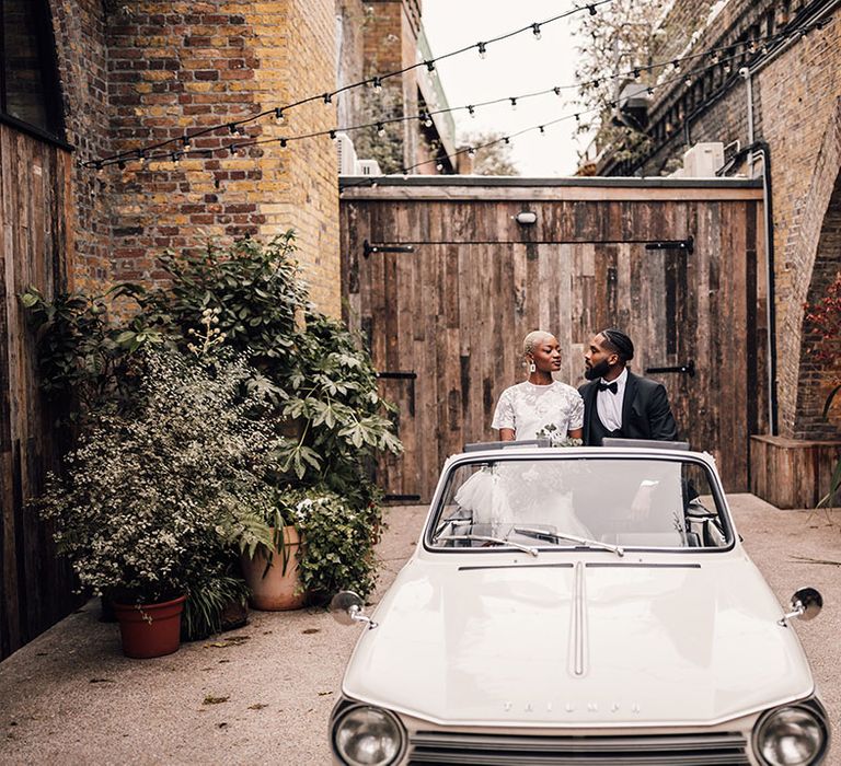 Black Bride and Groom sit in classic vintage wedding car at Industrial venue, 100 Barrington