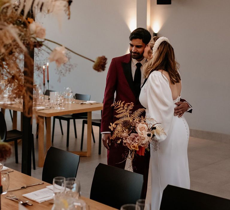 The bride kisses the groom on the cheek as they get their first look at the wedding decor for the reception at Crumplebury 