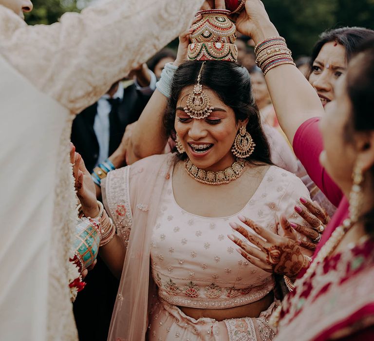 Wedding guest wears pale pink sherwani with embellishment during Hindu traditions outdoors 