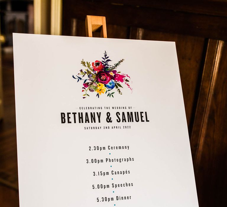 Order Of The Day wedding signage with colourful floral illustration on wooden easel 