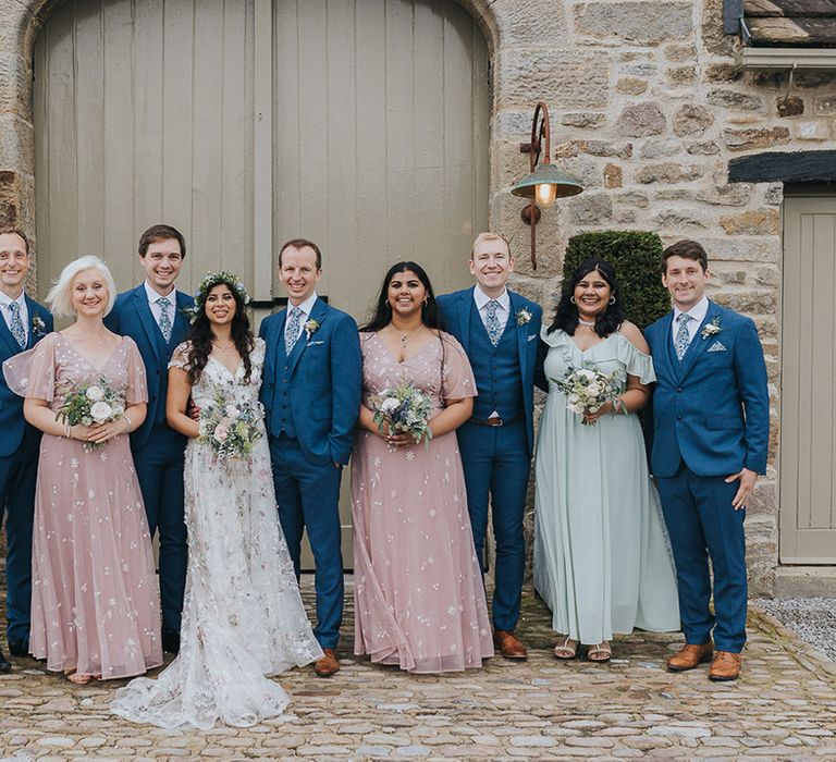 wedding party in pastel pink and blue dresses and groomsmen in navy blue suits 