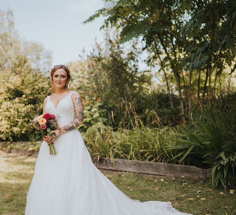 Bride in a lace wedding dress with colourful wedding bouquet 