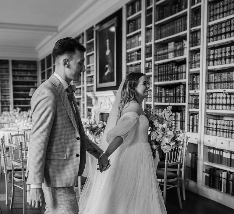 The bride and groom exit from their wedding breakfast in the library of St Giles House 