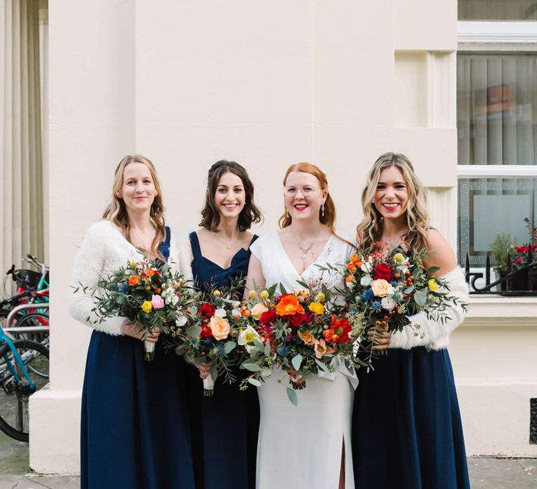 Navy bow bridesmaid dresses with white furry shawls and bride in traditional wedding dress for city wedding 