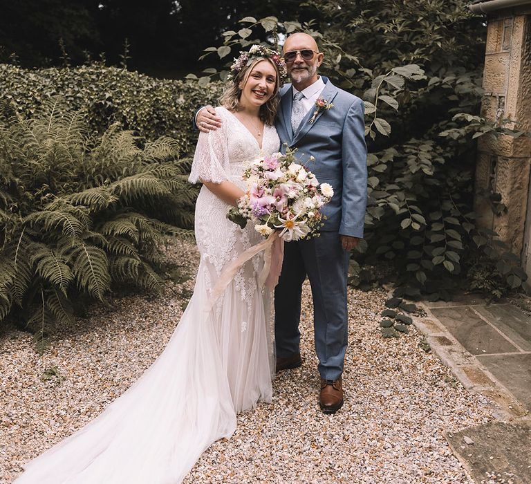 Father of the bride in blue suit and epic sunglasses embracing the bride as he sees her in her bridal outfit for the first time 