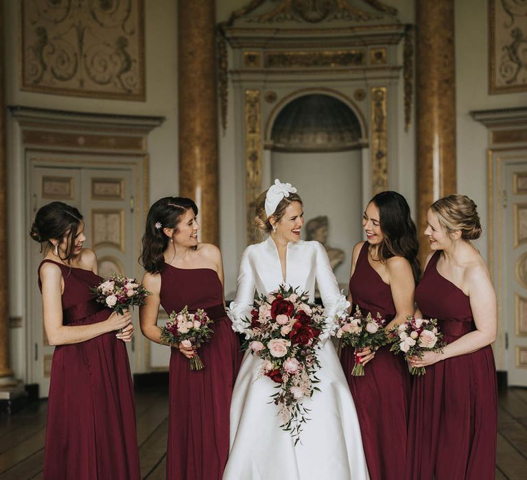 Classic traditional country house wedding with the bride in a high neck wedding dress with bridesmaids in one shoulder red dresses