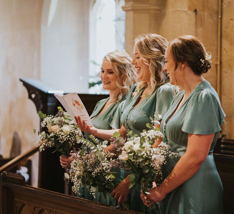 Bridal party wearing matching green satin bridesmaid dresses with short sleeves 