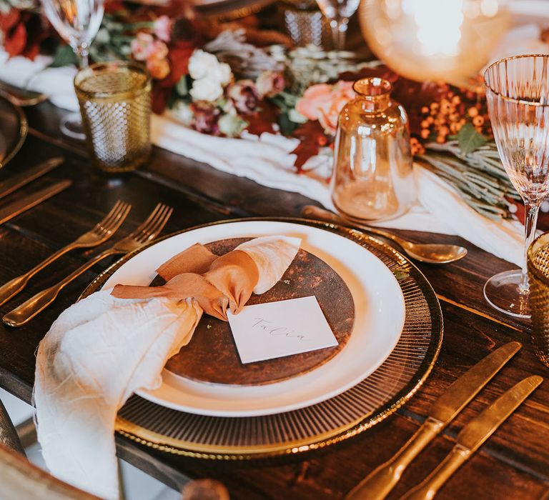 Gold charger plates, gold cutlery and gold rim wedding glasses with burnt orange napkin wedding tablescape 