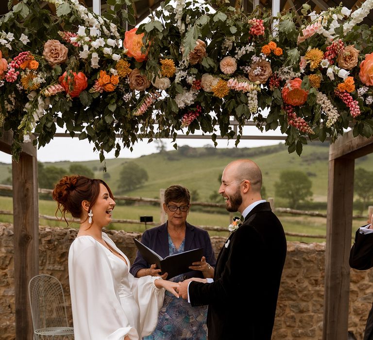 The bride and groom face each other for their outdoor wedding ceremony 