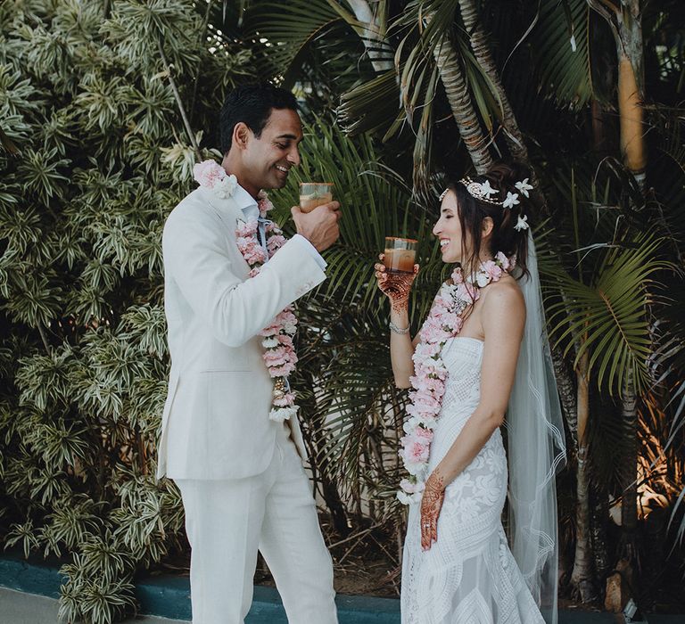 Bride in boho lave wedding dress and groom in cream wedding suit drinking cocktails together at Tigre Del Mar wedding